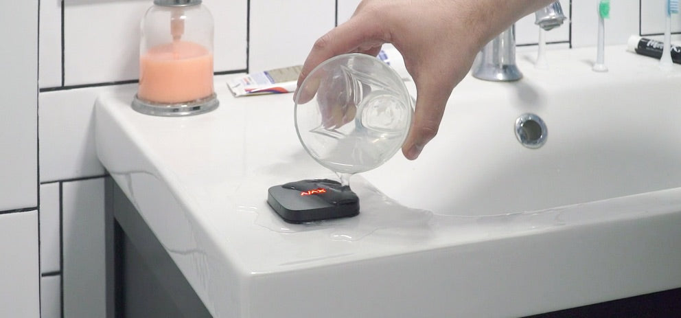 Detector Wireless Inundatii AJAX LeaksProtect testat cu apă pe blatul unei băi, ideal pentru protecția locuinței tale.